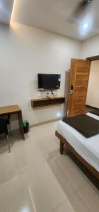 a bedroom with a bed and a flat screen tv at SRI KRISHNA LODGE in Hosūr