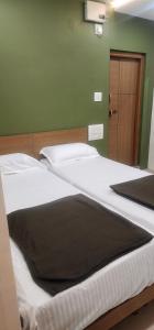 two beds in a bedroom with a green wall at SRI KRISHNA LODGE in Hosūr