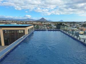 a large swimming pool with a view of a city at Lumea Apartment in Flic-en-Flac