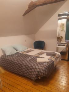 a large bed in a room with a black chair at Le studio de la Fontaine in Évron