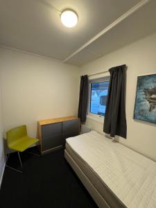 a bedroom with a bed and a chair and a window at Siggjo Guesthouse Bømlo and Stord in Mosterhamn