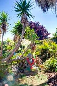 een standbeeld zittend op een rots onder een palmboom bij Chambres d'hôte Ô Bois Plage in Gujan-Mestras