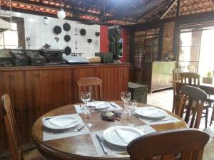 a wooden table with plates and wine glasses on it at Hotel Pousada Cata Branca in Itabirito