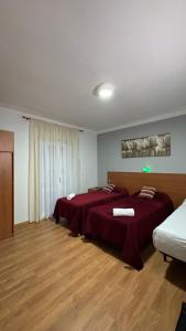 a bedroom with two beds with red sheets at Pensión Laforja in Barcelona