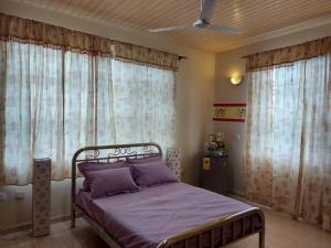 a bedroom with a bed with purple sheets and curtains at Osprise Residencies in Tema