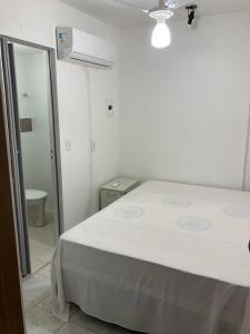 a white room with a bed and a bathroom at Quarto sala Centro in Guarapari