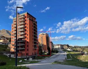 a tall red building next to a street at Cima Bianca Suite in Passo del Tonale