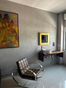 a bathroom with a chair and a sink and a painting at Kundera Hotel Boutique in Colima
