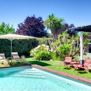 een zwembad in een tuin met stoelen en een parasol bij Chambres d'hôte Ô Bois Plage in Gujan-Mestras
