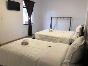 2 Letti in una camera ospedaliera con lenzuola bianche di Tikva Hotel a Cuenca