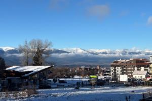 a snow covered city with mountains in the background at Ski-in Flat Next to Ski Road at Mountain View in Bansko