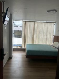 a bedroom with a bed and a large window at Hostal Bryana Inn Baños in Baños