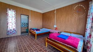 a room with two beds and two tables in it at Kalden Homestay Sinji in Kalimpong