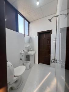 a bathroom with a toilet and a sink and a shower at Elysium Inn in Abbottabad