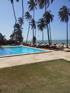 a swimming pool next to a beach with palm trees at Eco Paradise 227 in Cumbuco