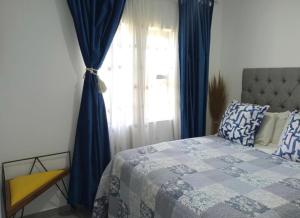 a bedroom with a bed and a window with blue curtains at Bee Bee Adventures in Ballito