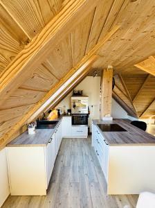 an attic kitchen with white cabinets and wooden ceilings at Psí bouda Benecko in Benecko