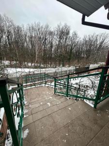 a green railing on a patio with snow on the ground at Заміський будинок кімната студія Pet - friendly in Mukacheve