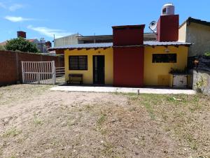 a small yellow and red house with a fence at Monoambiente in Mar de Ajó