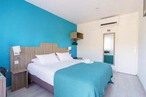 een slaapkamer met een groot bed met een blauwe muur bij Brit Hotel Confort Manosque Cadarache in Manosque +98 foto's