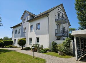 a large white building with balconies and a yard at Apartmenthaus Ostseeluft in Lohme