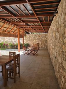 a patio with tables and chairs and a stone wall at Hotel El Paraíso Calakmul in Xpujil