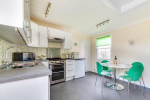 a kitchen with white cabinets and a table with green chairs at 3 Bed in Woodbridge oc-tst in Melton
