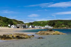a beach with rocks in the water and houses at 3 Bed in Morfa Nefyn oc-wag720 in Morfa Nefyn