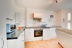 a white kitchen with white appliances and a couch at 1 Bed in Sheringham oc-2033 in Sheringham +2 photos