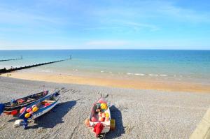 two boats sitting on a beach next to the ocean at 1 Bed in Sheringham oc-2033 in Sheringham