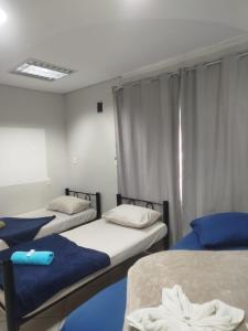 a room with three beds and a window at Pousada Central Quarto 1 in Joinville