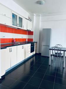 een keuken met witte kasten, een tafel en een koelkast bij Bella Home Apartment in Roşu