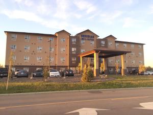 a hotel with cars parked in a parking lot at Meridian Inn & Suites Lloydminster in Lloydminster