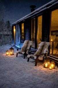 two chairs in the snow next to a cabin with lights at Palas Experience Olkkajärvi Resort in Rovaniemi