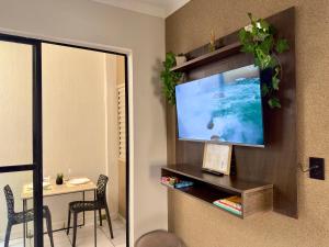 a room with a television on a wall with a table at Apartamento Central in Passos