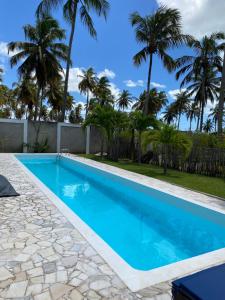 a swimming pool with palm trees in the background at Coco Ville SMG in São Miguel do Gostoso