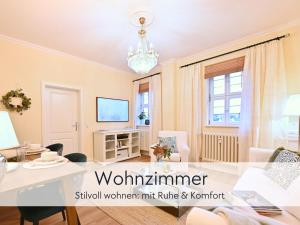 a living room with a table and a chandelier at Amalias Burgwohnung - stilvolles Apartment mit Aufzug & Garten in der Hinterburg Schlitz - 2 Schlafzimmer, Parkplatz, Historisches Flair für Paare & Ruhesuchende in Schlitz