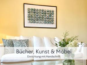 a living room with a white couch with a picture on the wall at Amalias Altstadtquartier - Apartment mit Aufzug & Garten in der Hinterburg Schlitz - 2 Schlafzimmer, Parkplatz, Altstadtflair für Paare & Ruhesuchende in Schlitz