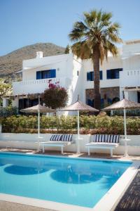 a pool with chairs and umbrellas next to a building at White Blue Villa formerly Ippocampi in Koutouloufari
