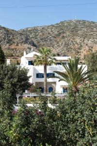a white building with palm trees in front of it at White Blue Villa formerly Ippocampi in Koutouloufari