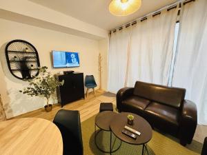 a living room with a leather couch and a table at La coloc' l 3 Chambres avec salle de bain & TV in Castres