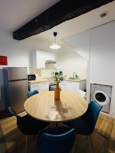a kitchen with a wooden table and blue chairs at La coloc' l 3 Chambres avec salle de bain & TV in Castres