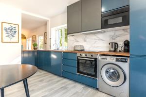 a kitchen with blue cabinets and a washer and dryer at Carregado First Floor in Carregado