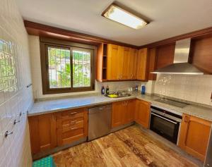 a kitchen with wooden cabinets and a sink and a window at Luna-Villa de Riviera with Sea-View in Mijas Costa