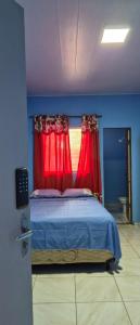 a bedroom with a bed with red curtains and a window at Casa do ViajanteBr in Barreirinhas +12 photos