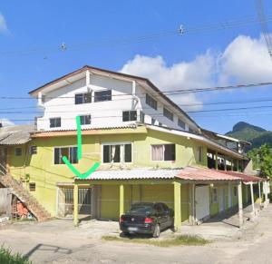 a yellow and white building with a car parked in front at Casa da praia dois irmãos in Matinhos