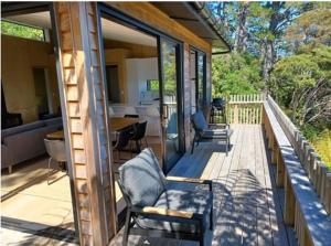 a porch of a house with chairs and a table at Ponga House - Kaitoke Waters in Okupu