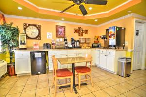 eine Küche mit einem Tisch, Stühlen und einer Uhr in der Unterkunft Sunset Inn in Jacksonville