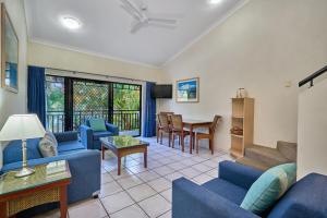 a living room with blue couches and a table at Trinity Beach Club Holiday Apartments in Trinity Beach