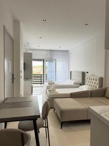 a white room with four beds and a table and chairs at Maison Apartments in Vlorë +138 photos